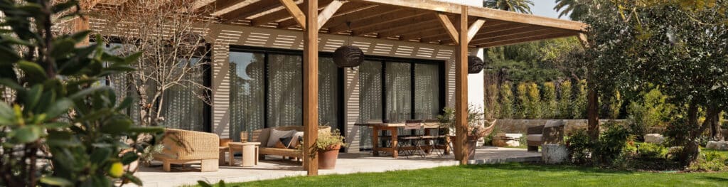 Terrasse moderne : pergola bois, mobilier rotin et jardin paysager ensoleillé.
